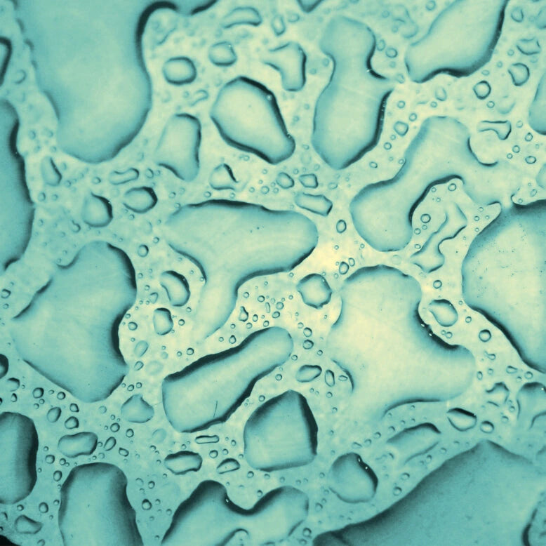 Age-Defying Mist droplets on a textured surface with a teal color.