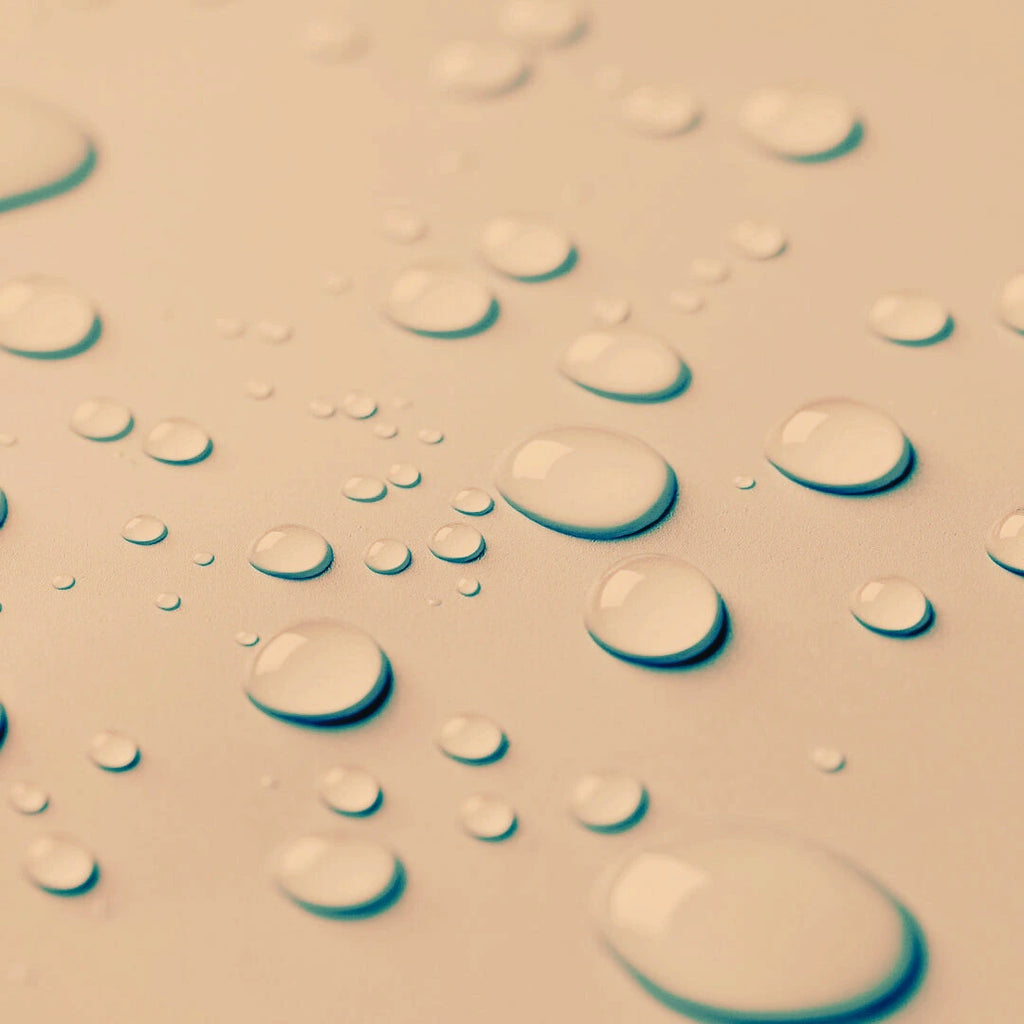 Close-up of water droplets for the Blemish Control Mist on a textured surface