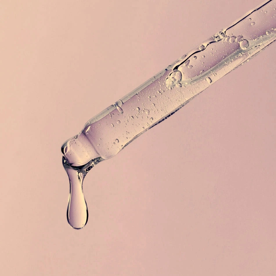 Close-up of a dropper with the C Serum on a pink background