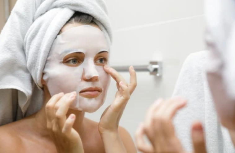 Woman applying facial mask in front of a mirror